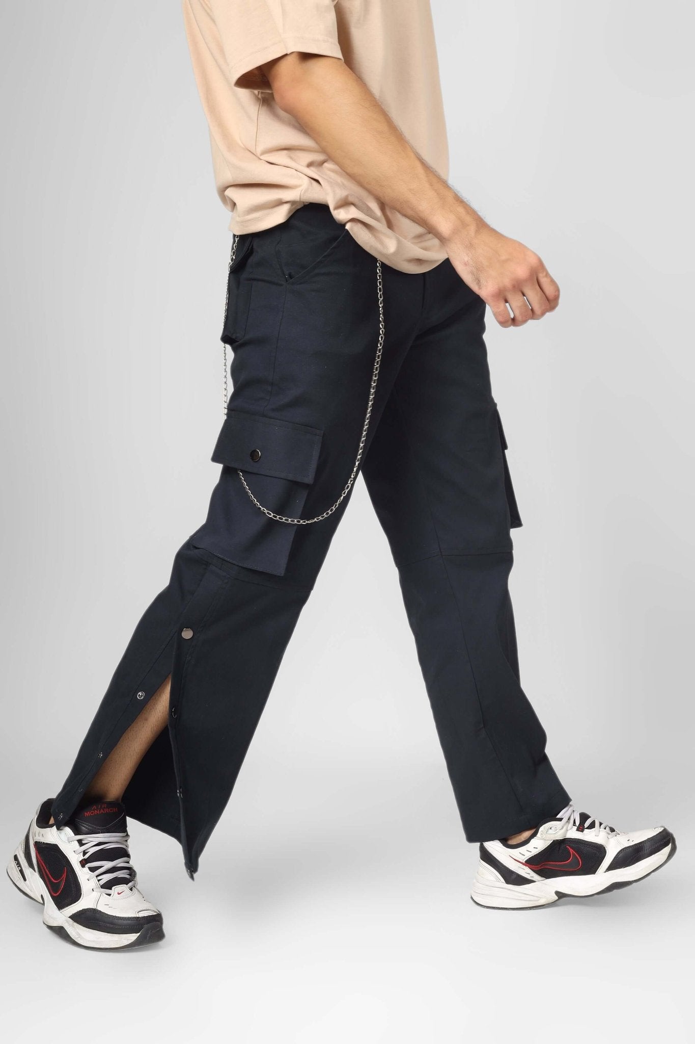 Man wearing OXFORD BLUE CARGO PANTS WITH 6 POCKET, showcasing streetwear style with sneakers and chain accent.