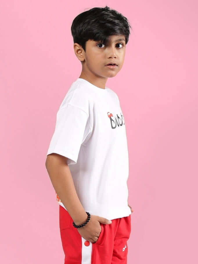 Young boy wearing Paloma T-Shirt for boys girls white, standing against a pink background.