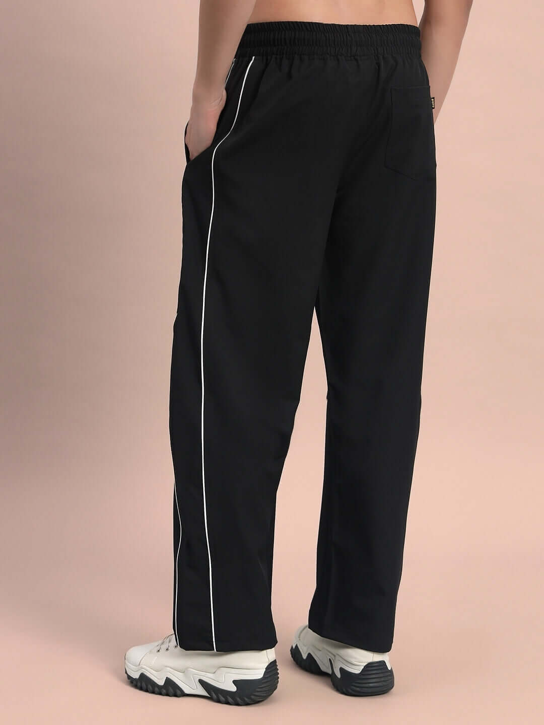 Model wearing black parabolic parachute cargo pants with white side piping, showcasing the back design.