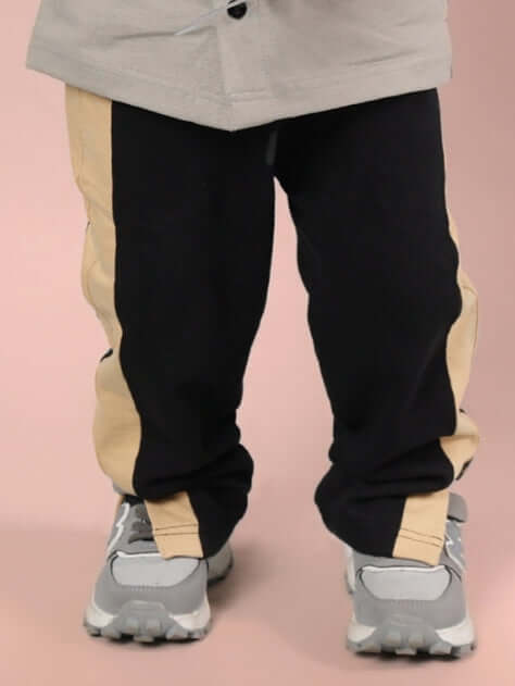 Child wearing PARADISE JOGGER FOR BOYS & GIRLS BLACK BEIGE in a stylish pose.