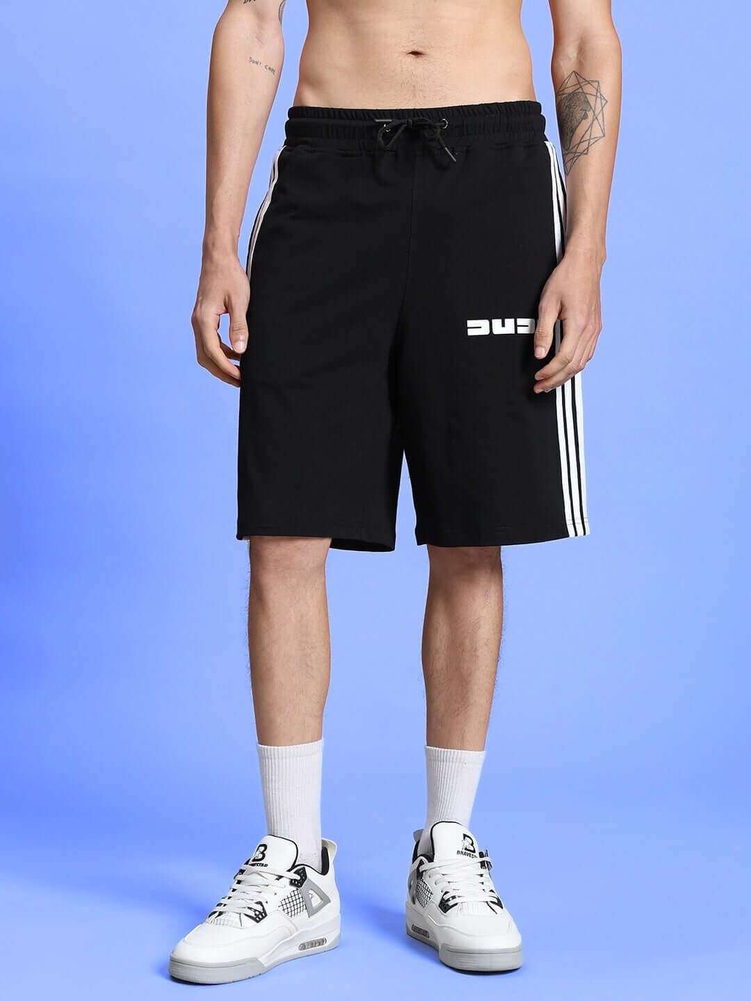 Person wearing PARKA REGULAR FIT SHORTS BLACK, showcasing versatile and comfortable design for everyday wear in front of a blue background.
