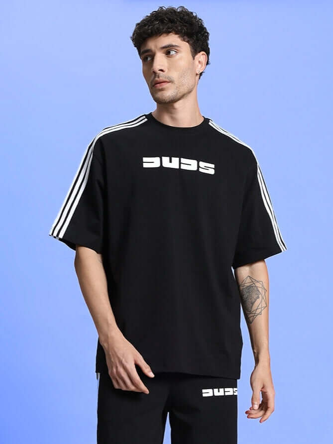 Man wearing PARKA OVER-SIZED CLASSIC T-SHIRT BLACK, relaxed fit, premium cotton, versatile black, male fashion.
