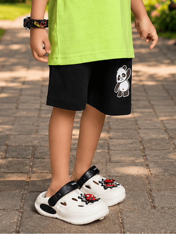 Child wearing PEEK-A-PANDA COOL SHORTS FOR BOYS GIRLS BLACK and playful shoes, enjoying outdoor playtime.