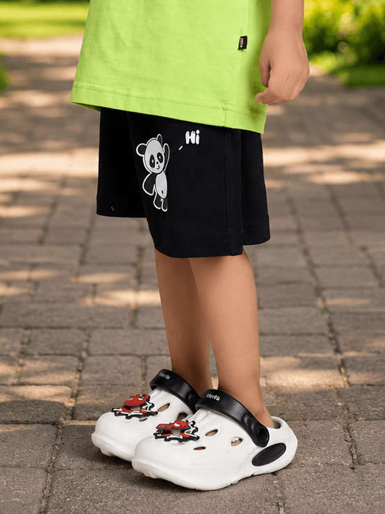 PEEK-A-PANDA COOL SHORTS FOR BOYS GIRLS BLACK worn by child with white clogs in a playful outdoor setting.