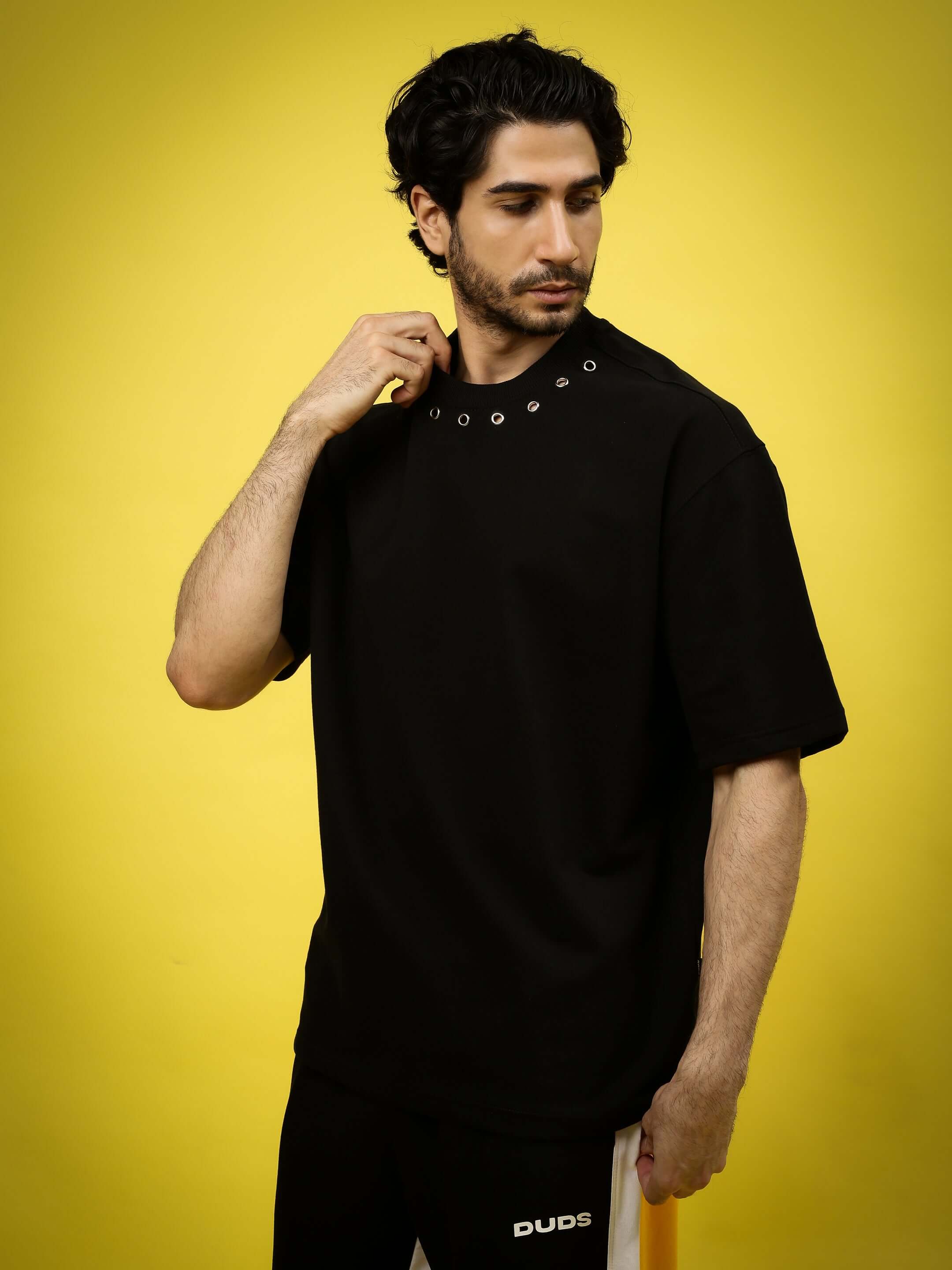 Model wearing DUDS black oversized t-shirt against yellow background