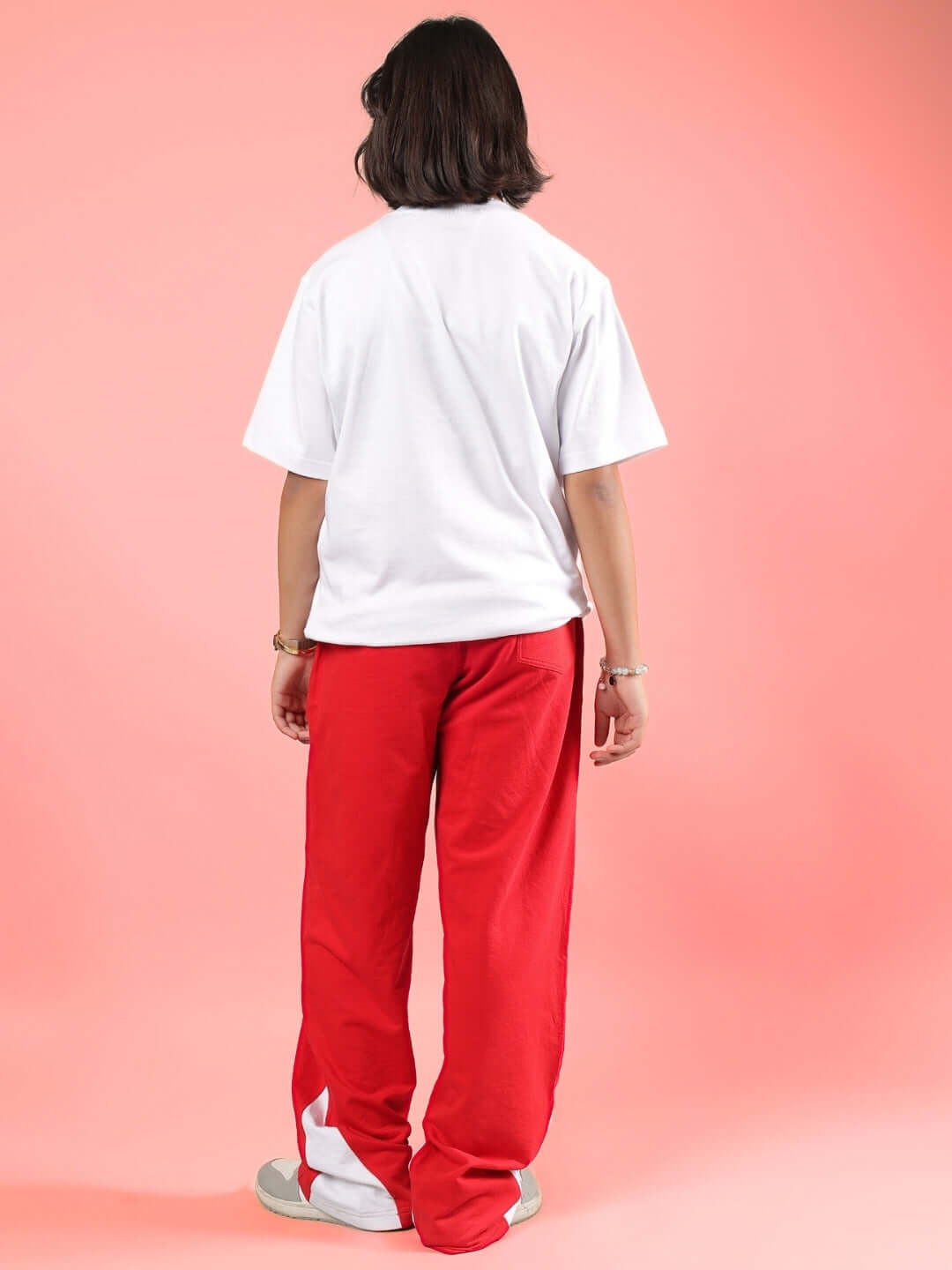 Child wearing the PETER CO-ORD FOR BOYS & GIRLS WHITE-RED outfit, featuring a white top and red pants, standing with a pink background.