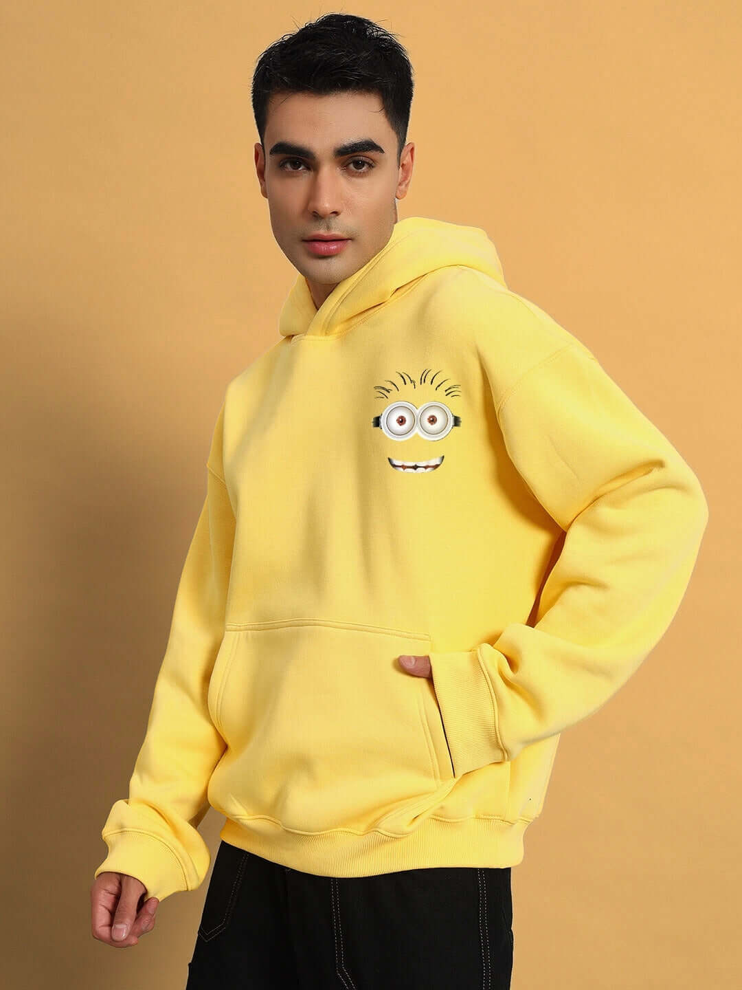 Man wearing PHIL MINION OVERSIZED FLEECE HOODIE YELLOW, showcasing vibrant design and playful comfort in a cozy, oversized fit.