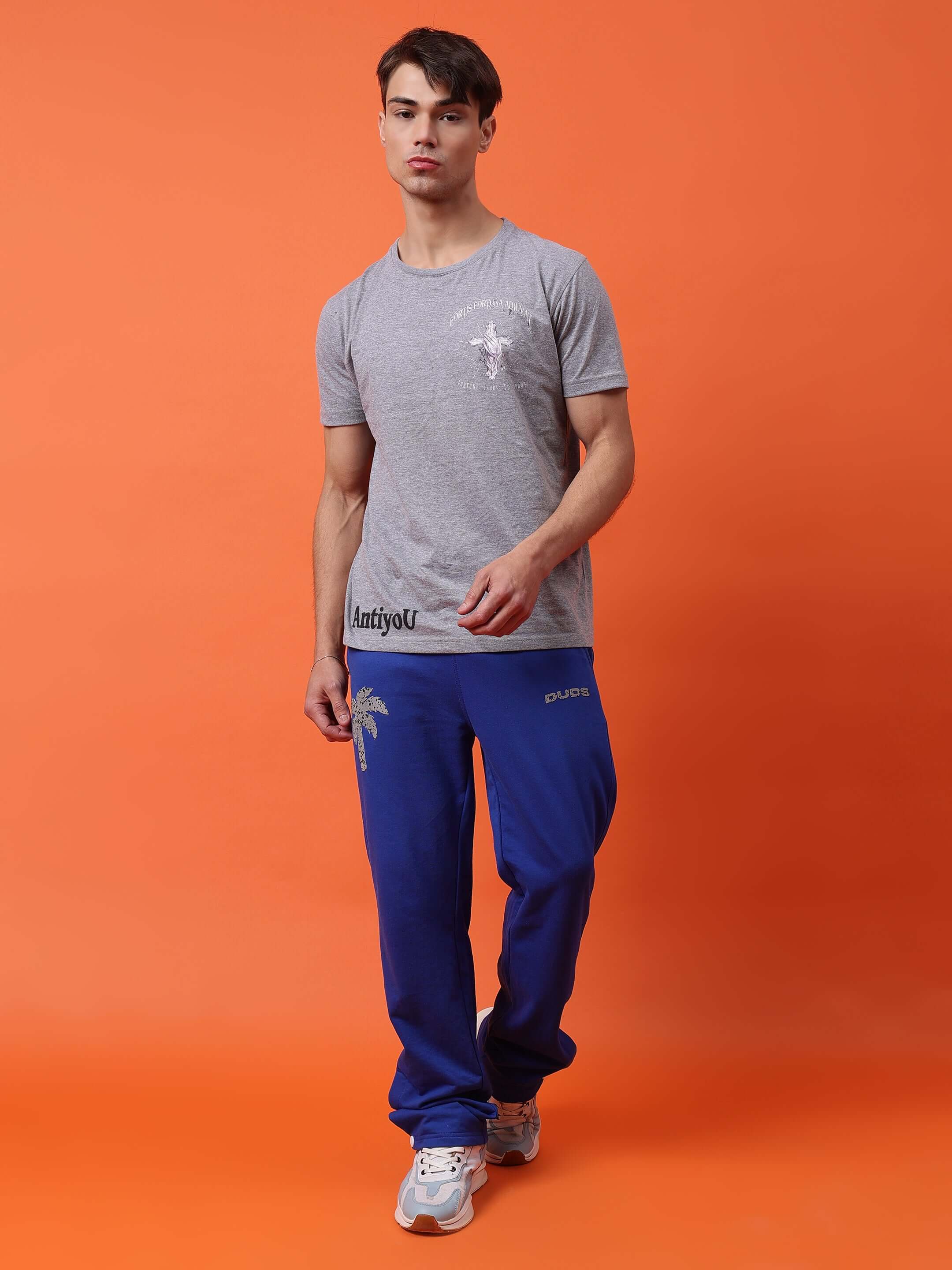 Model wearing Phoenix digital printed joggers in royal blue, paired with a gray t-shirt, on an orange background.