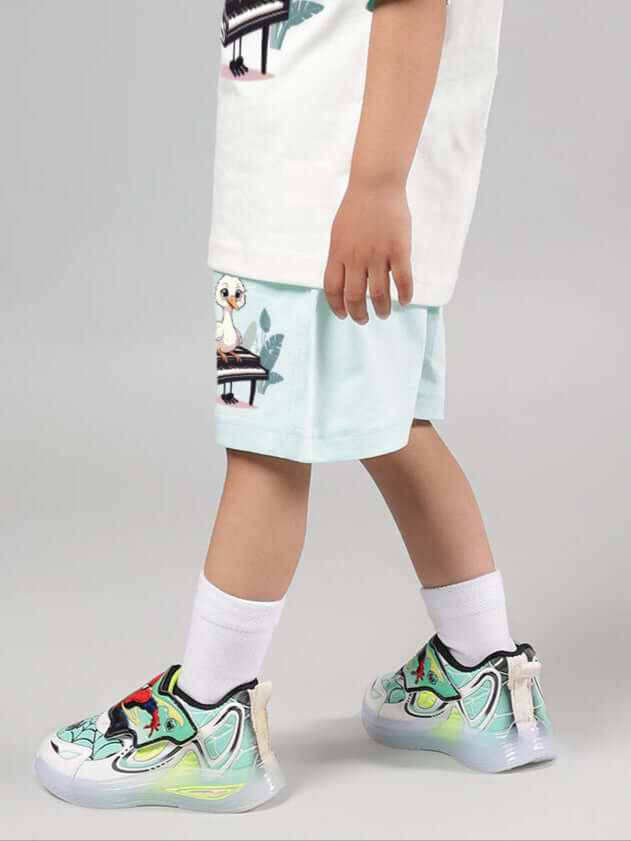 Child wearing Piano Bird Shorts for Boys Girls Sky Blue, walking with colorful sneakers in a studio.