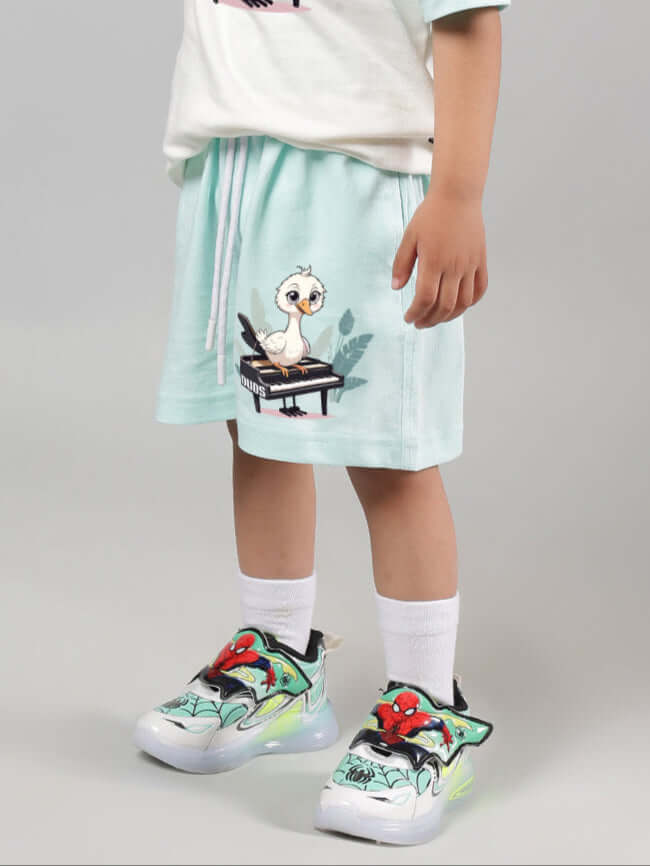 Sky blue Piano Bird shorts for boys & girls, featuring a cute bird design playing piano, styled with vibrant sneakers on a child.