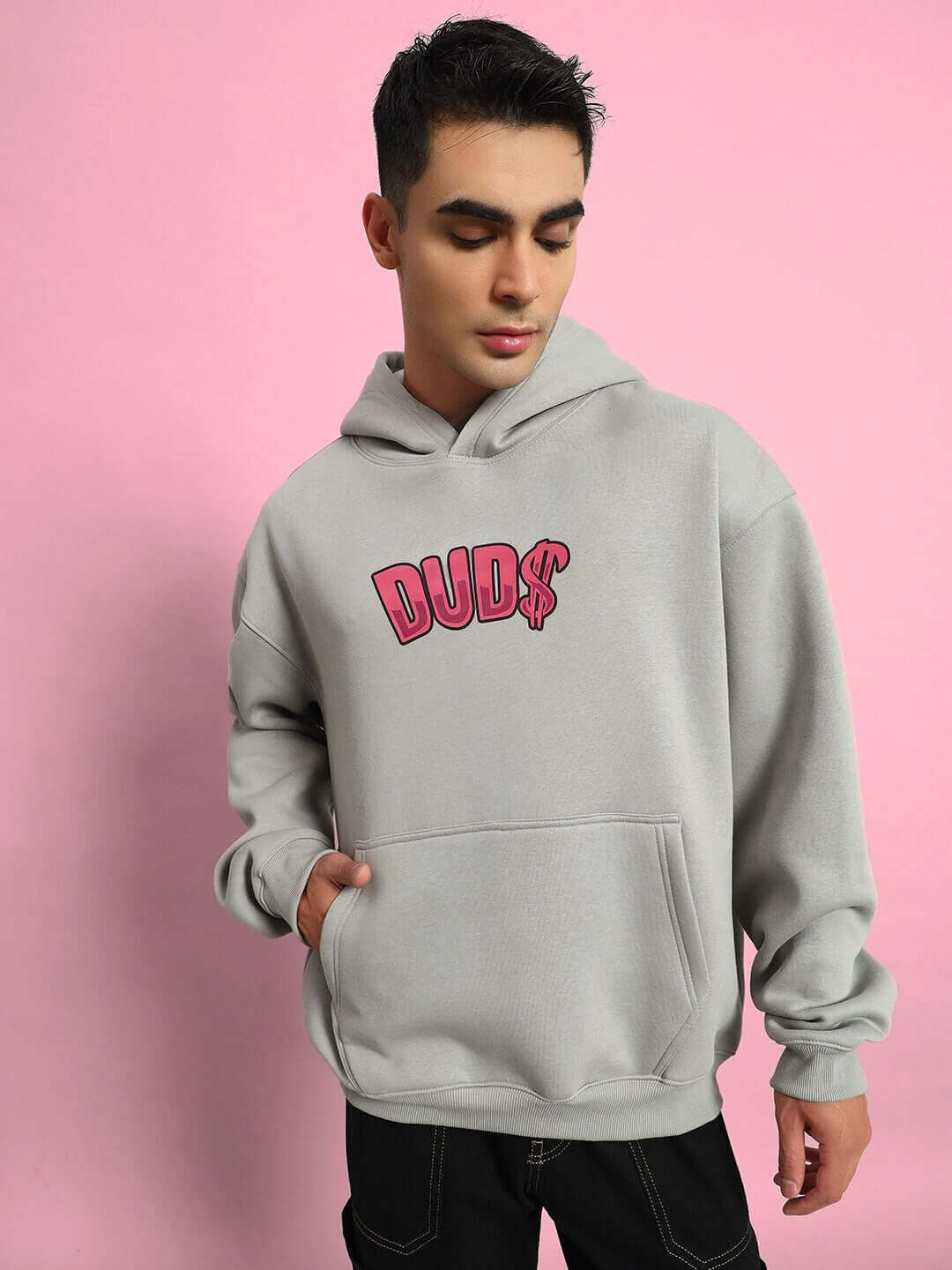Man wearing PINK PANTHER FLEECE OVERSIZED HOODIE GREY with pink graphic, standing against a pink background.