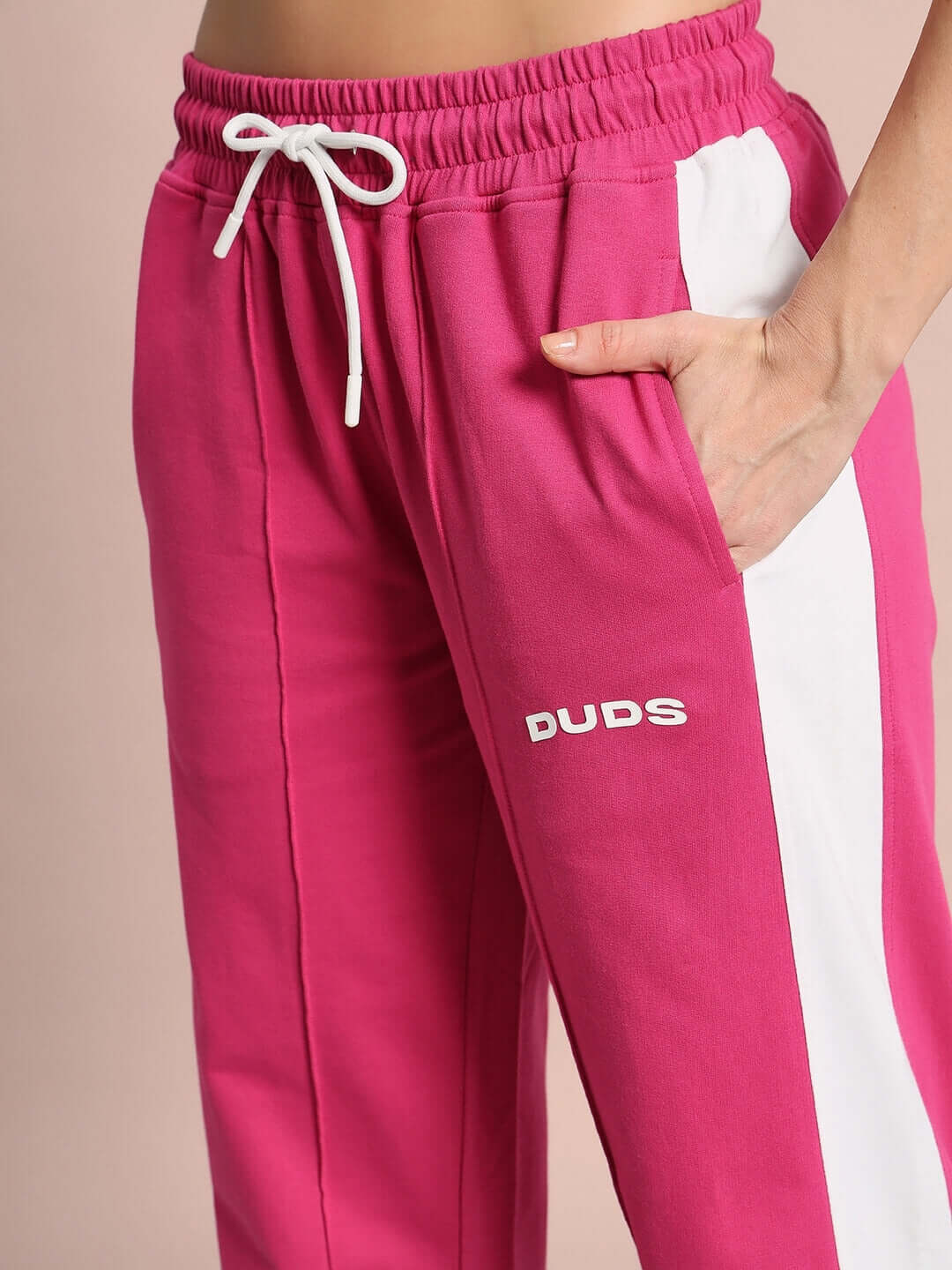 Women's pink joggers with white side seam and DUDS logo, featuring elastic waistband and drawstring detail.
