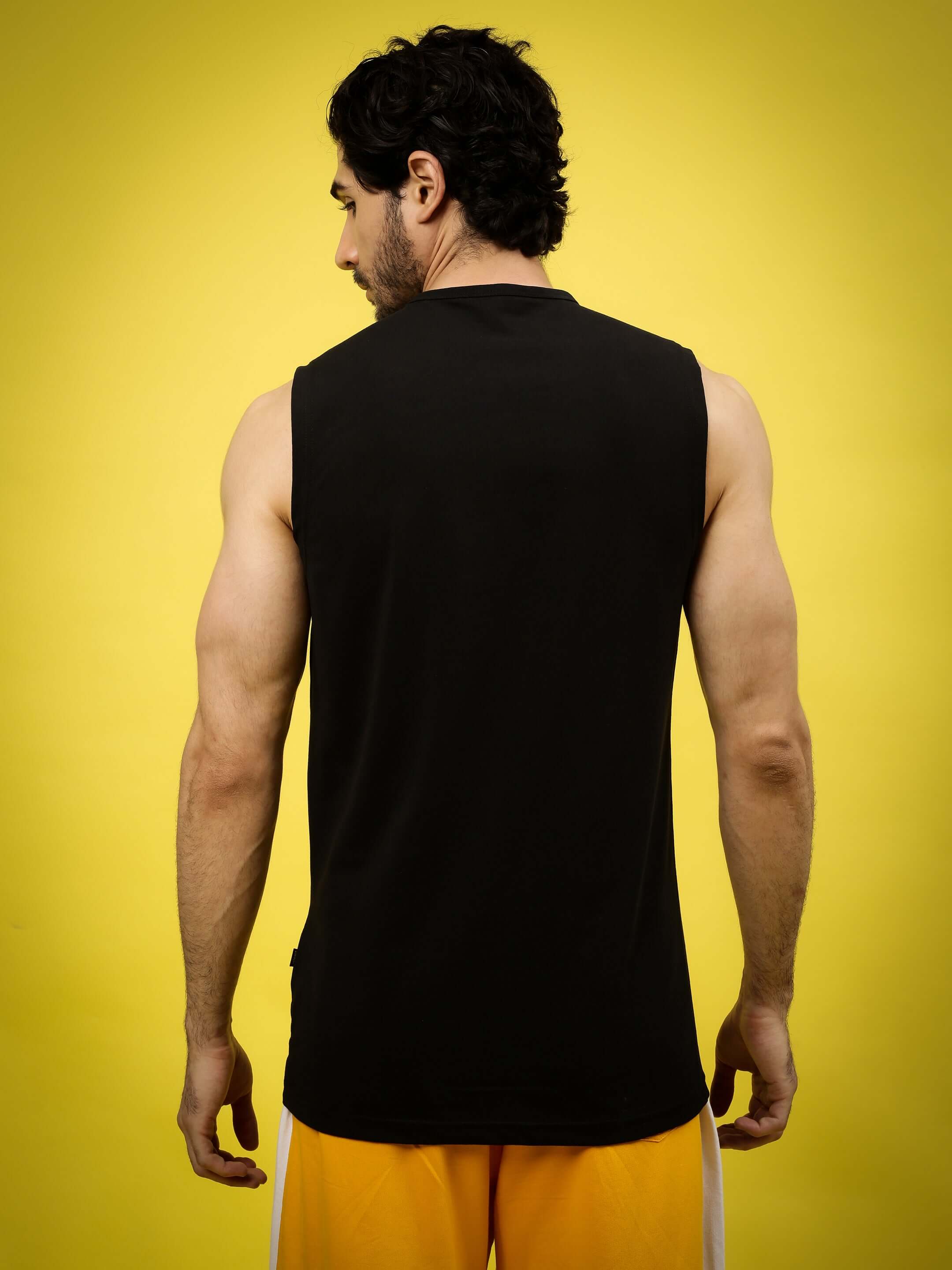 Back view of man wearing a black Pinnacle Regular Fit T-shirt against a yellow background, highlighting custom fit option.