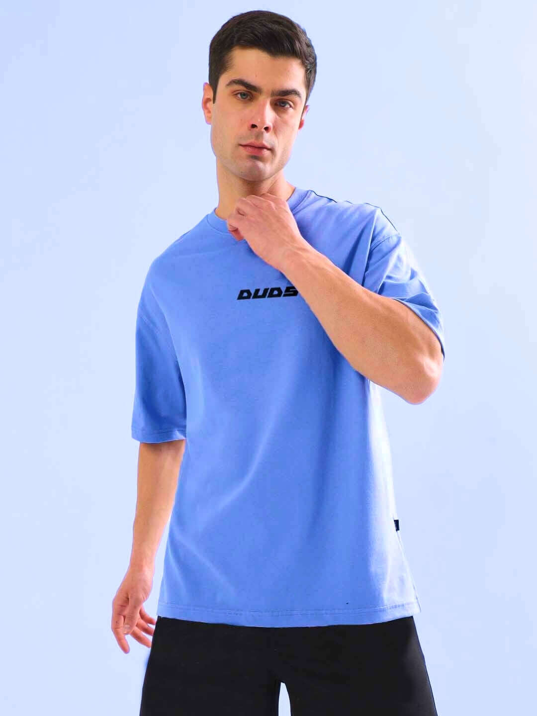Model wearing a cobalt blue oversized t-shirt in premium cotton fabric, showcasing a casual style against a light blue background.