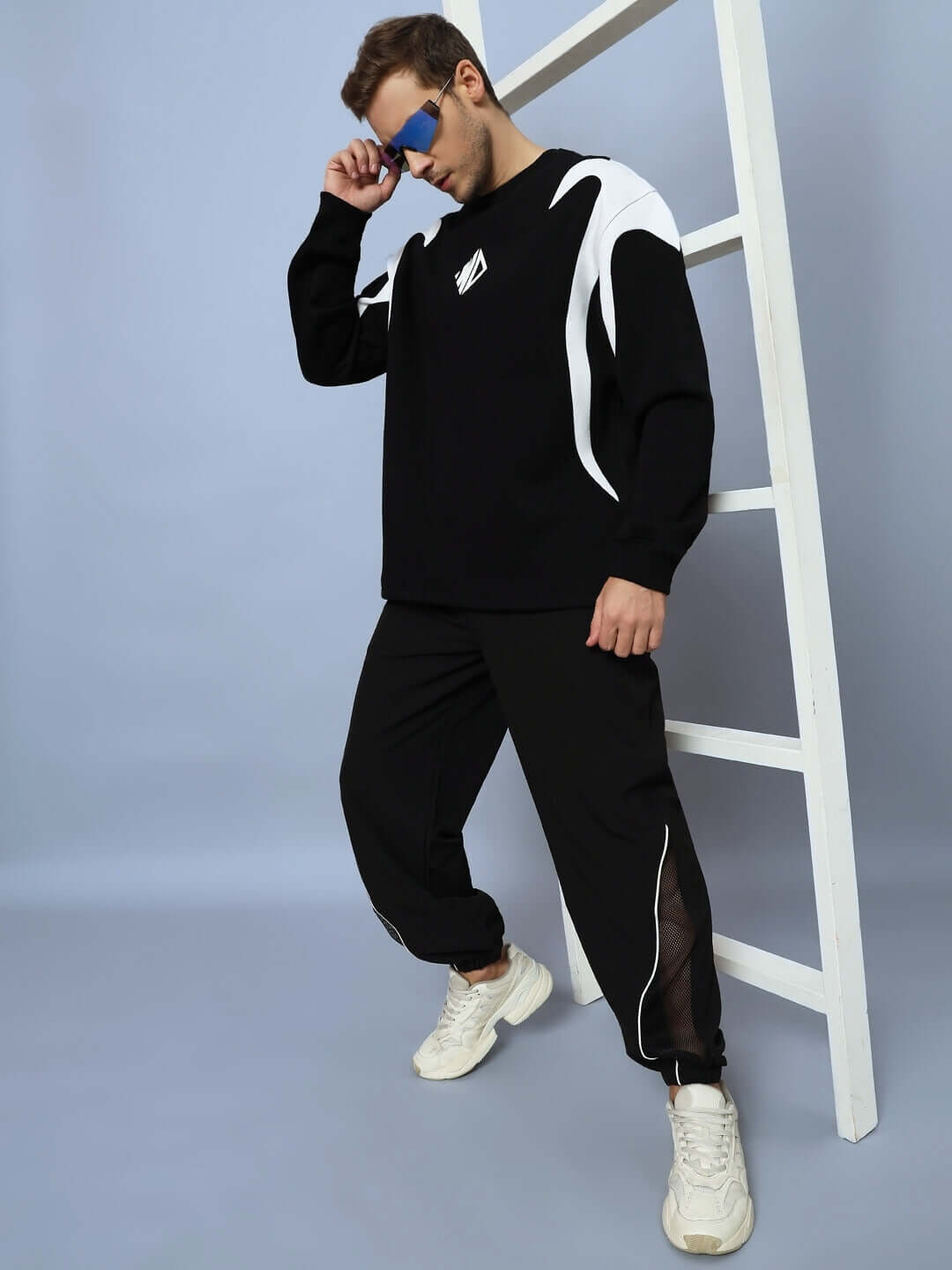 Fashionable model wearing black PLEXUS joggers and matching top, showcasing a stylish modern look with white sneakers.