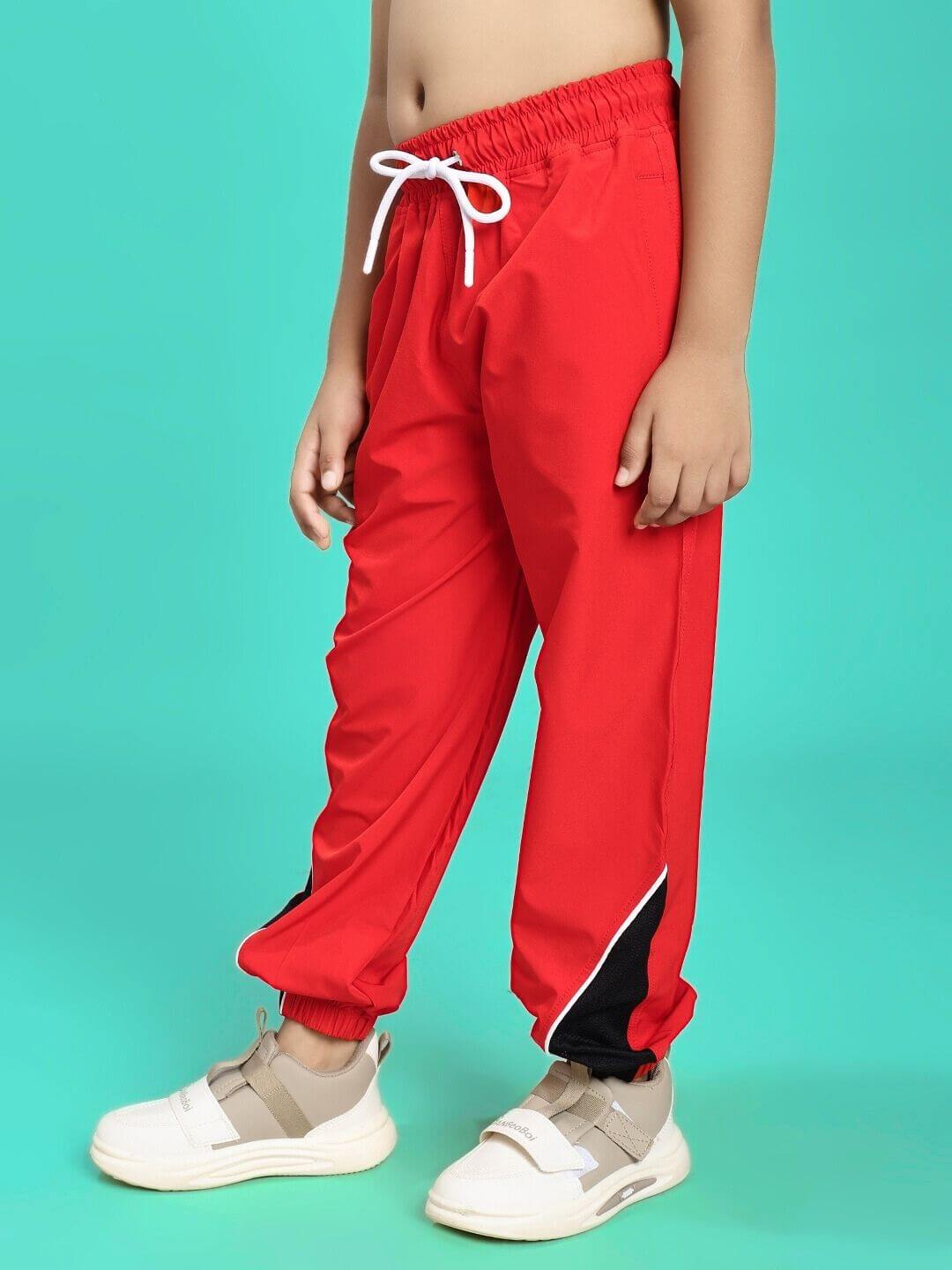 Child wearing PLEXUS JOGGER FOR BOYS AND GIRLS RED, showcasing vibrant red joggers with relaxed fit and white sneakers, perfect for active days.