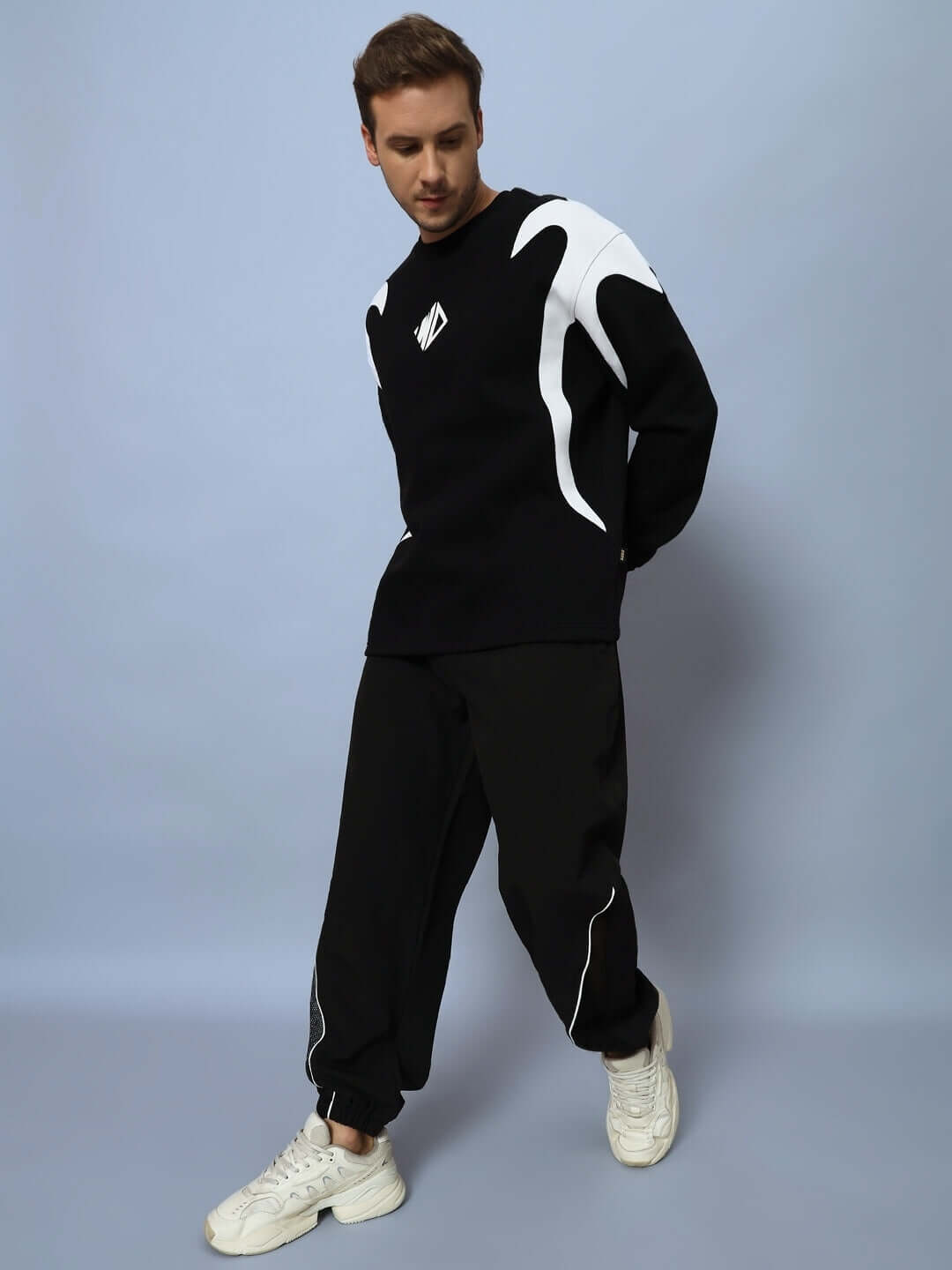 Man wearing DUDS PLEXUS joggers in black with matching sweatshirt against a light gray background.