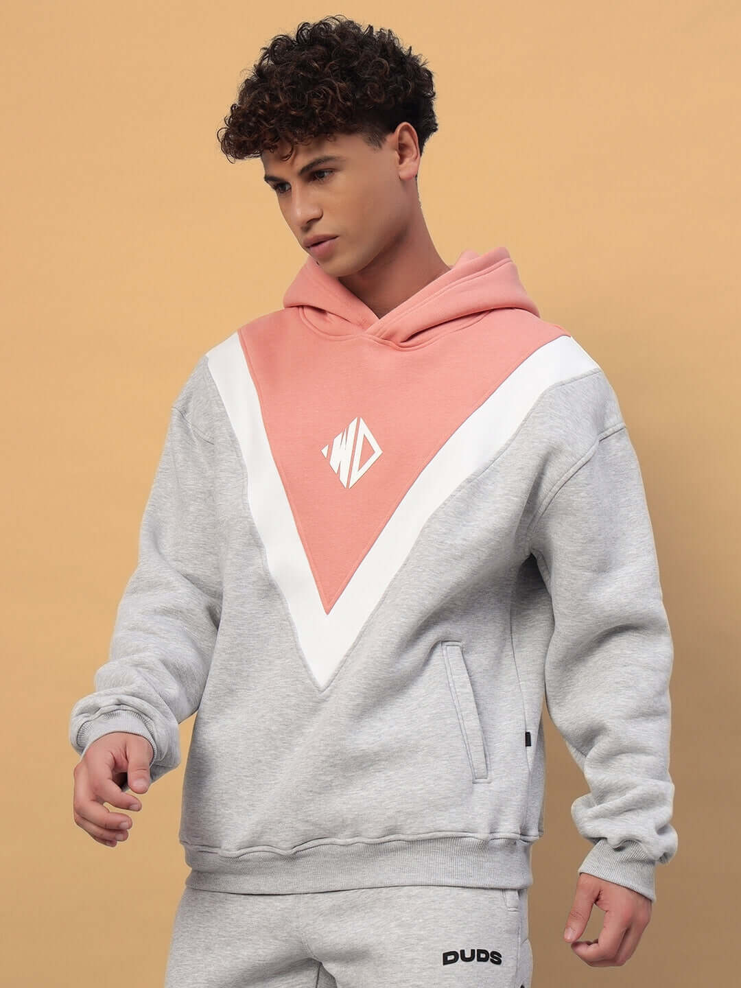 Man wearing POLAR FLEECE COLORBLOCK HOODIE GREY PEACH with a peach and grey design, showcasing modern streetwear fashion.