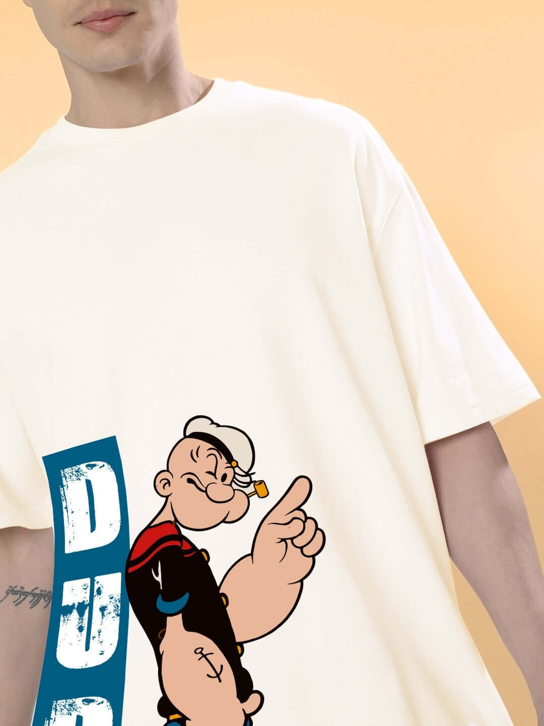 Cream Popeye oversized t-shirt with a unique design, customizable fit option, showcased on a mannequin against a peach background.