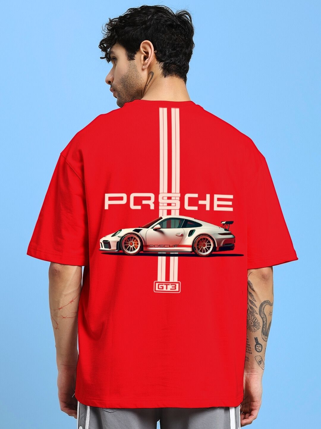 Man wearing PORSCHE PRINTED OVER-SIZED T-SHIRT RED with car graphic and logo on back, showcasing the vibrant design and comfortable fit.