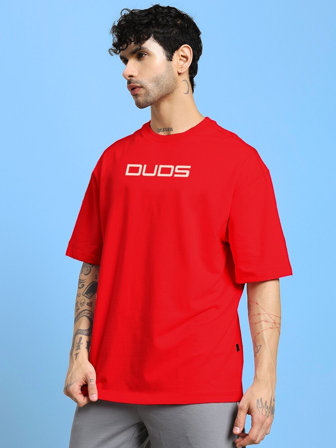 Model wearing a red PORSCHE PRINTED OVER-SIZED T-SHIRT RED with casual styling on a blue background.