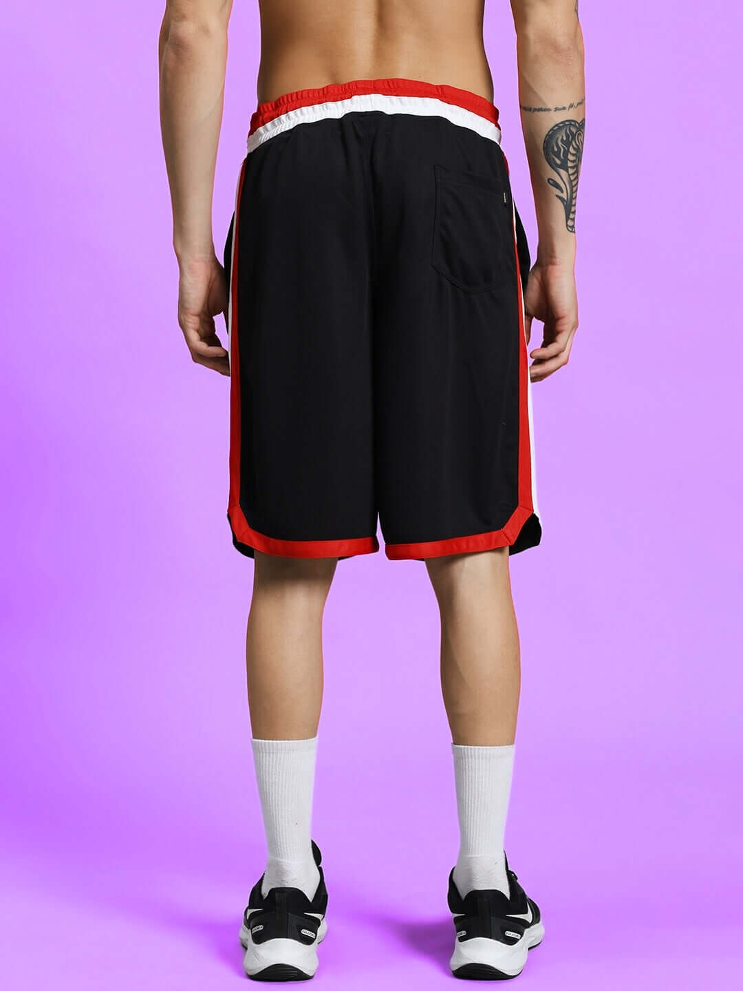 Rear view of PORTIA REGULAR FIT SHORTS BLACK with red trim on a model, showcasing sporty design and flexibility.