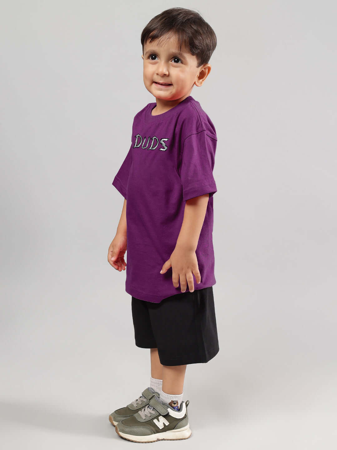 Child wearing POSITIVE RABBIT KIDS CO-ORD FOR BOYS GIRLS PURPLE-BLACK outfit, showcasing purple top and black shorts.