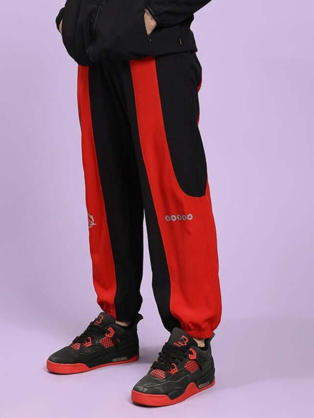 POWER BLOCK RELAXED FIT JOGGER BLACK RED Person wearing black and red tracksuit with visible brand logo on a light purple background