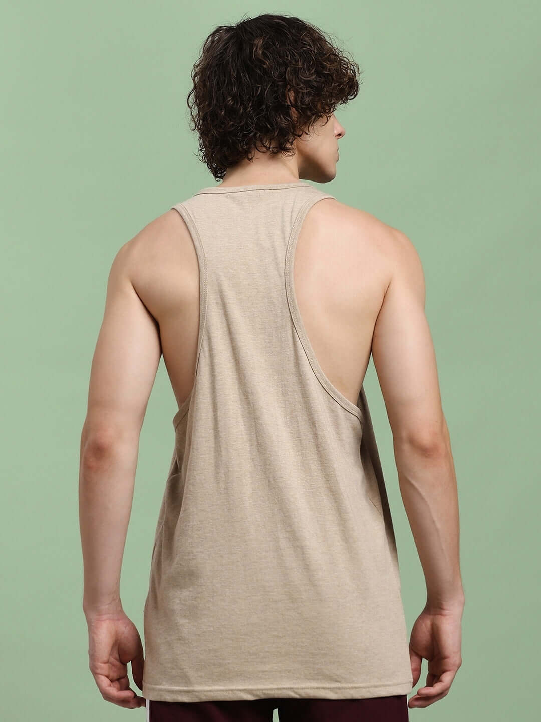 Back view of a model wearing a beige Powerfit fitness gym T-shirt, showcasing custom fit options for personalized workout comfort.