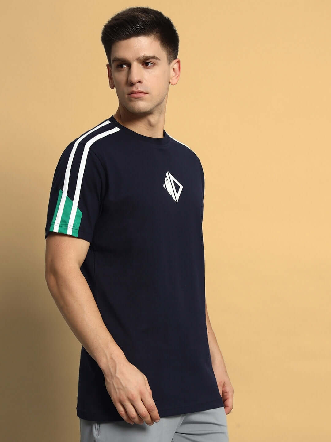 Model wearing Prima Regular T-Shirt in navy blue and green, featuring premium cotton French terry fabric, side view against beige background.