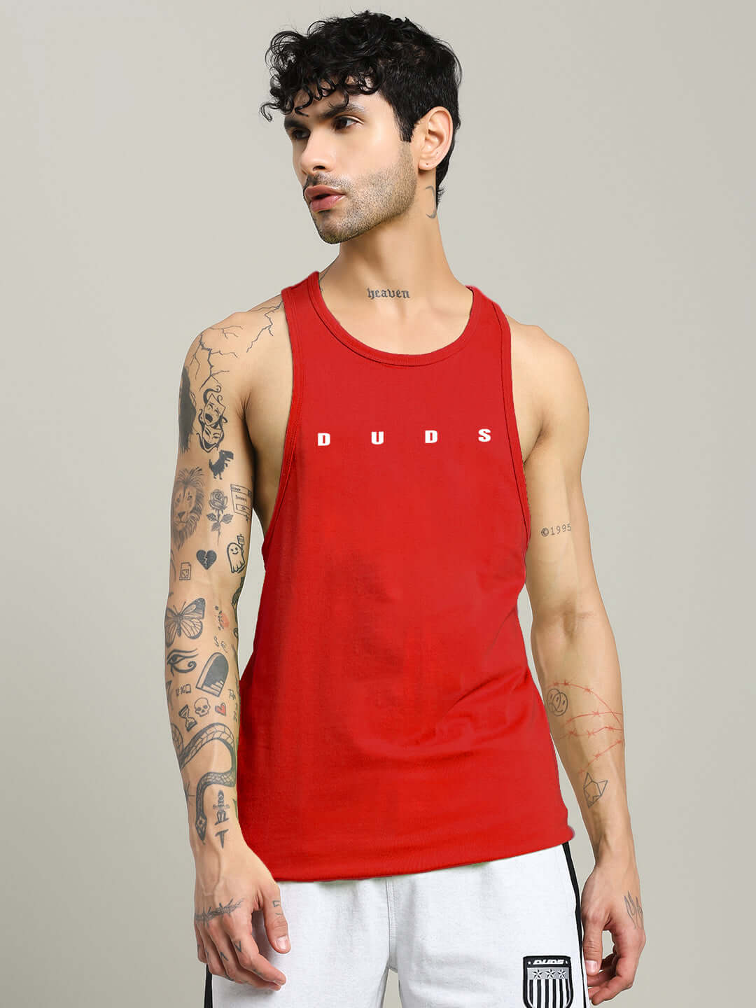 Alt Tag: Man wearing a red PRIMO GYM T-SHIRT with DUDS logo, showcasing fitness apparel fashion.