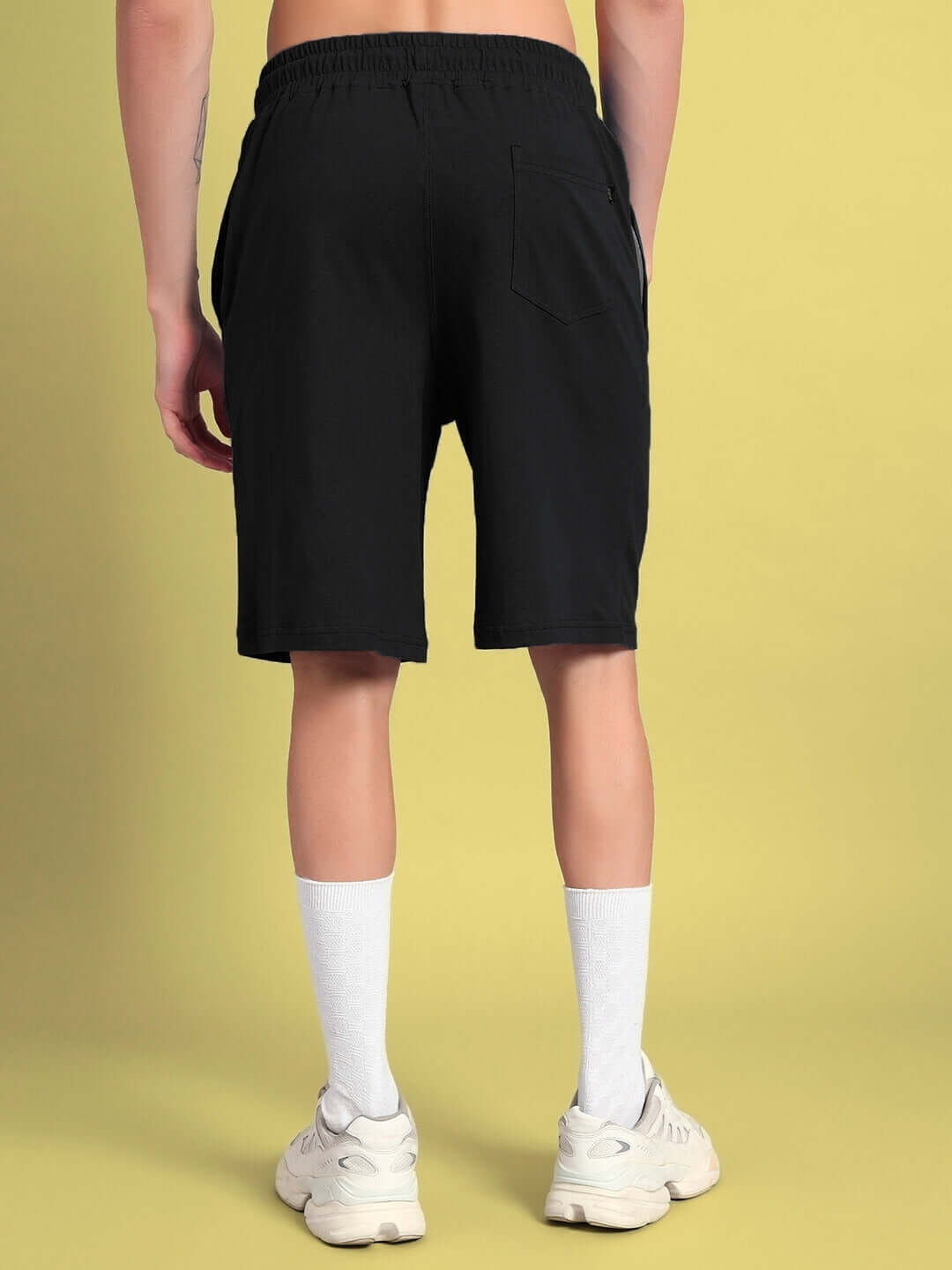 Back view of person wearing Quack Off Summer Shorts in black, showcasing elastic waistband and pocket details for custom fit option.