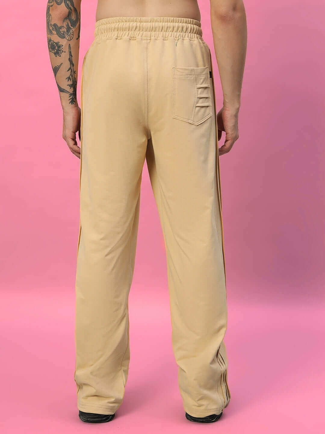 Rear view of Quantum Relaxed-Fit Joggers in beige, featuring elastic waistband and pocket detail, displayed against a pink background.