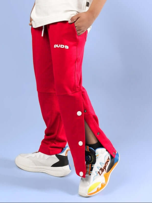 Child wearing RACER JOGGER FOR BOYS & GIRLS RED by DUDS, featuring buttoned leg and sneakers.