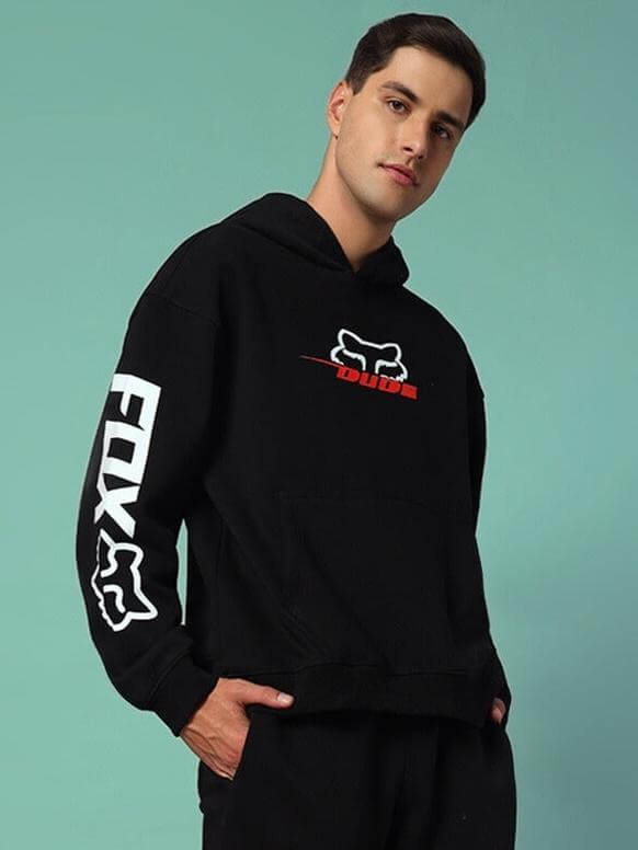 Man wearing RACING FOX COTTON FLEECE HOODIE BLACK with printed sleeves and logo, stylish streetwear fashion.