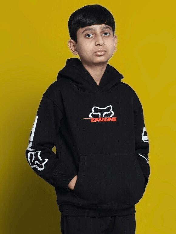 Boy wearing a black Racing Fox oversized hoodie with bold logo design on a vibrant yellow background.