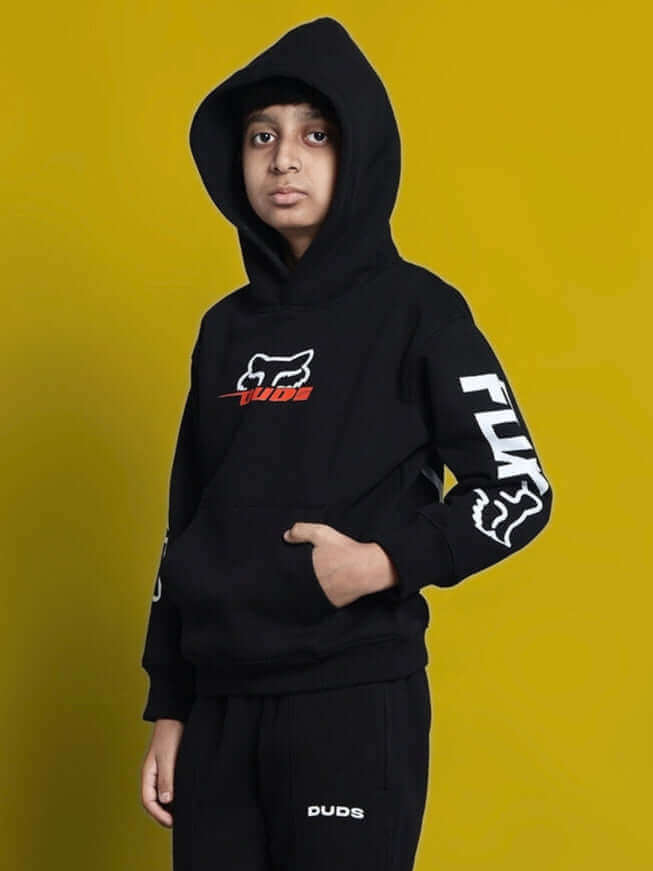 Child wearing Racing Fox oversized black hoodie for boys and girls with stylish logo on sleeve and chest, against yellow background.