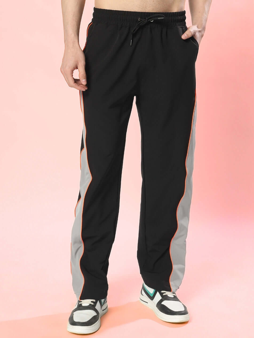 RAGE relaxed fit black-grey cargo pants with orange trim, customizable size options, worn with sneakers on pink background