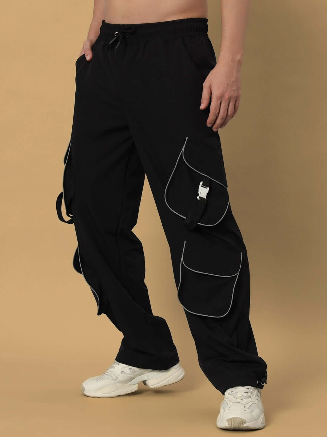 Black RAGGA REFLECTOR parachute cargo pants with multiple pockets and white piping, designed for custom fit and handmade craftsmanship.
