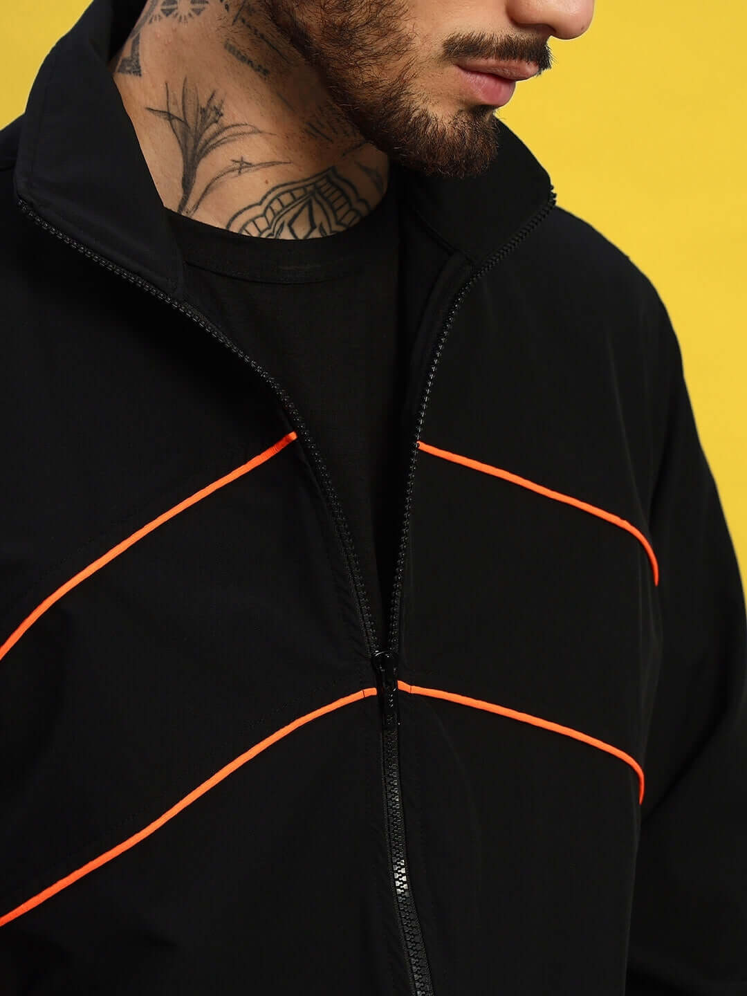 Close-up of a black Raider jacket with orange detailing, designed by DUDS, showcasing the craftsmanship of skilled tailors.