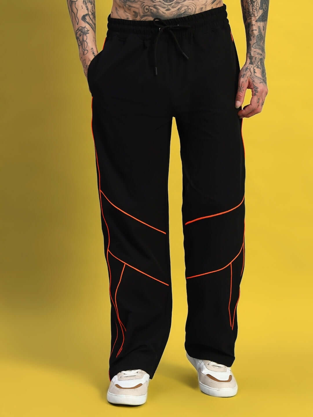 Man wearing black RAIDER RELAXED PANT JOGGER with red stitching, casually comfortable on yellow background.