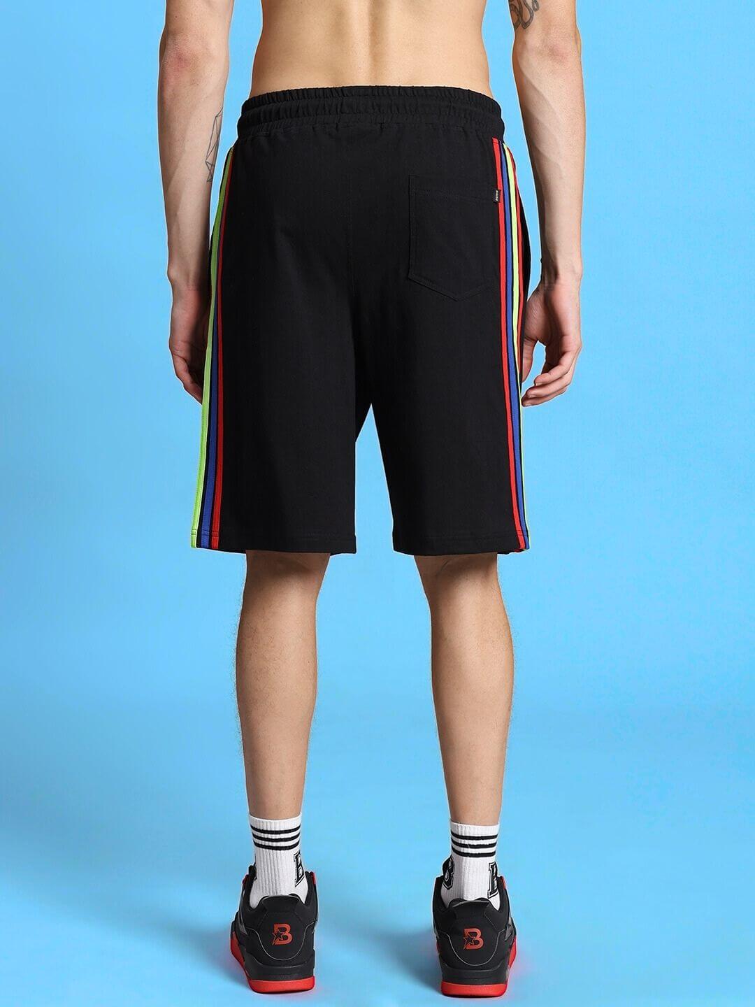 Back view of RAINBOW REGULAR FIT SHORTS BLACK with colorful side stripes, shown on a model, with option for custom fit adjustments.