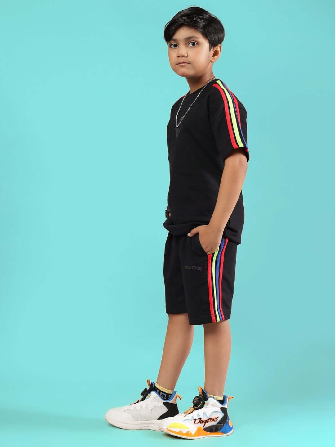 Child wearing RAINBOW SUMMER CO-ORD FOR BOYS & GIRLS BLACK, featuring rainbow stripes and casual style on a bright background.