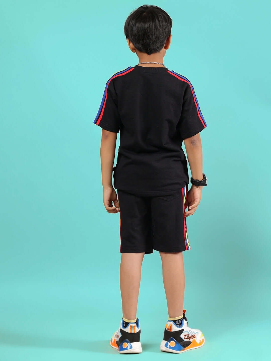 Child wearing RAINBOW SUMMER CO-ORD FOR BOYS & GIRLS BLACK, featuring colorful stripes on black fabric, back view.