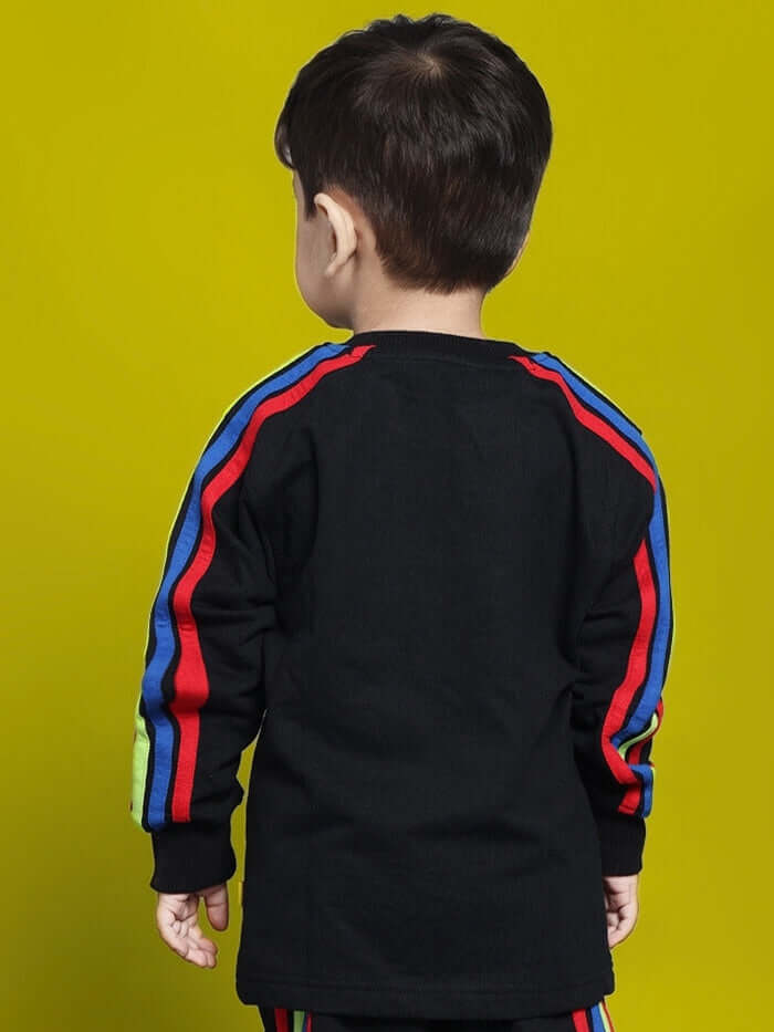 Child wearing RAINBOW OVERSIZED SWEATSHIRT BOYS & GIRLS BLACK with colorful stripes on a yellow background.