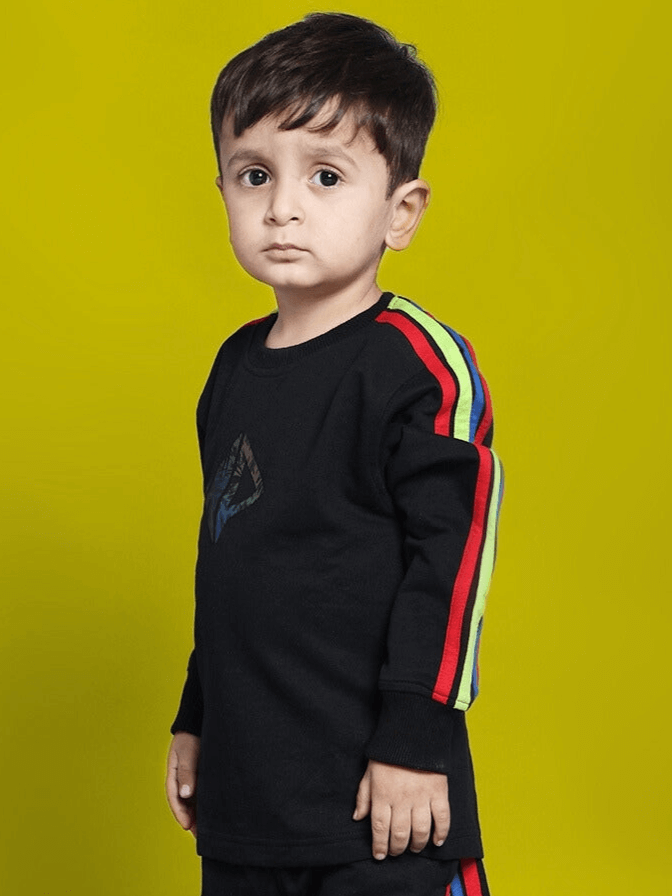 Child wearing RAINBOW OVERSIZED SWEATSHIRT BOYS & GIRLS BLACK with colorful sleeve stripes against yellow background.