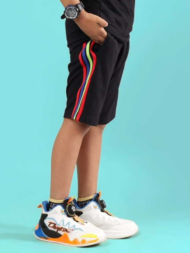 Child wearing RAINBOW SHORTS FOR BOYS & GIRLS BLACK with colorful sneakers.