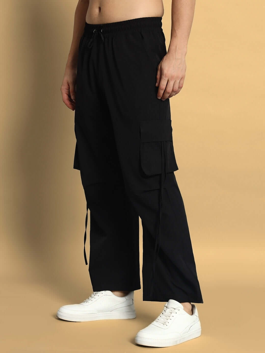 Person wearing black RAMROD parachute cargo pants with white sneakers.