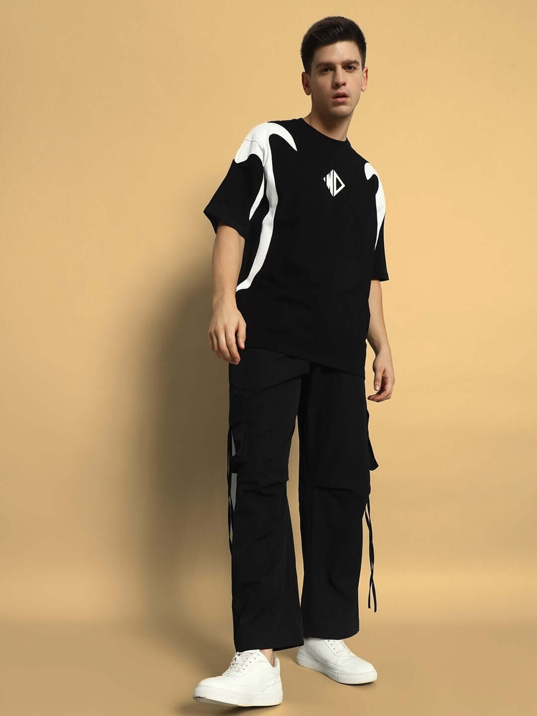 Model wearing RAMROD parachute cargo pants in black, featuring a casual, urban style, matched with a graphic black and white shirt.