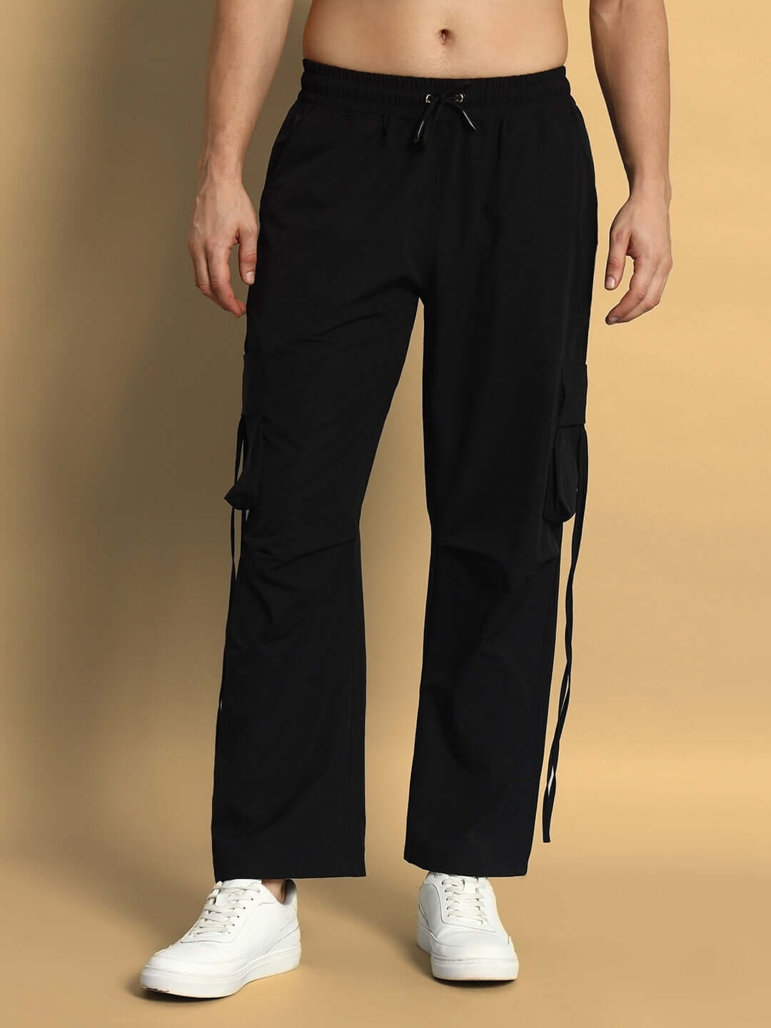 Model wearing RAMROD black parachute cargo pants with drawstring and side pockets, offering a customizable fit.